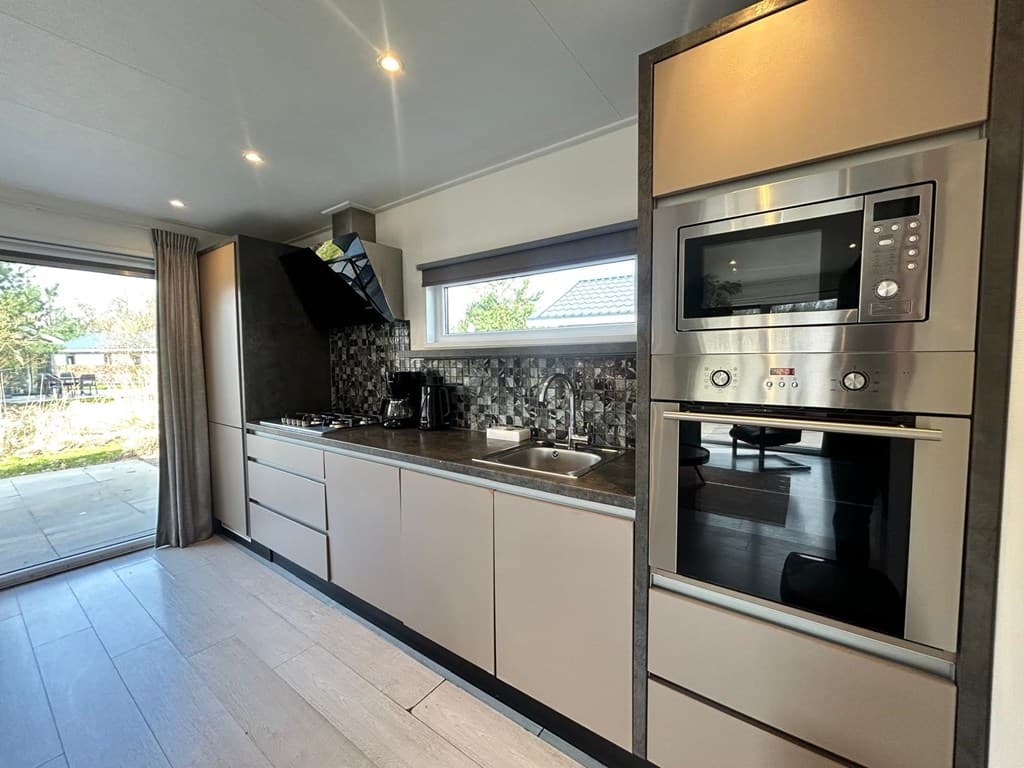 Moderne keuken met inbouwapparatuur, een gaskookplaat en openslaande deuren naar buiten