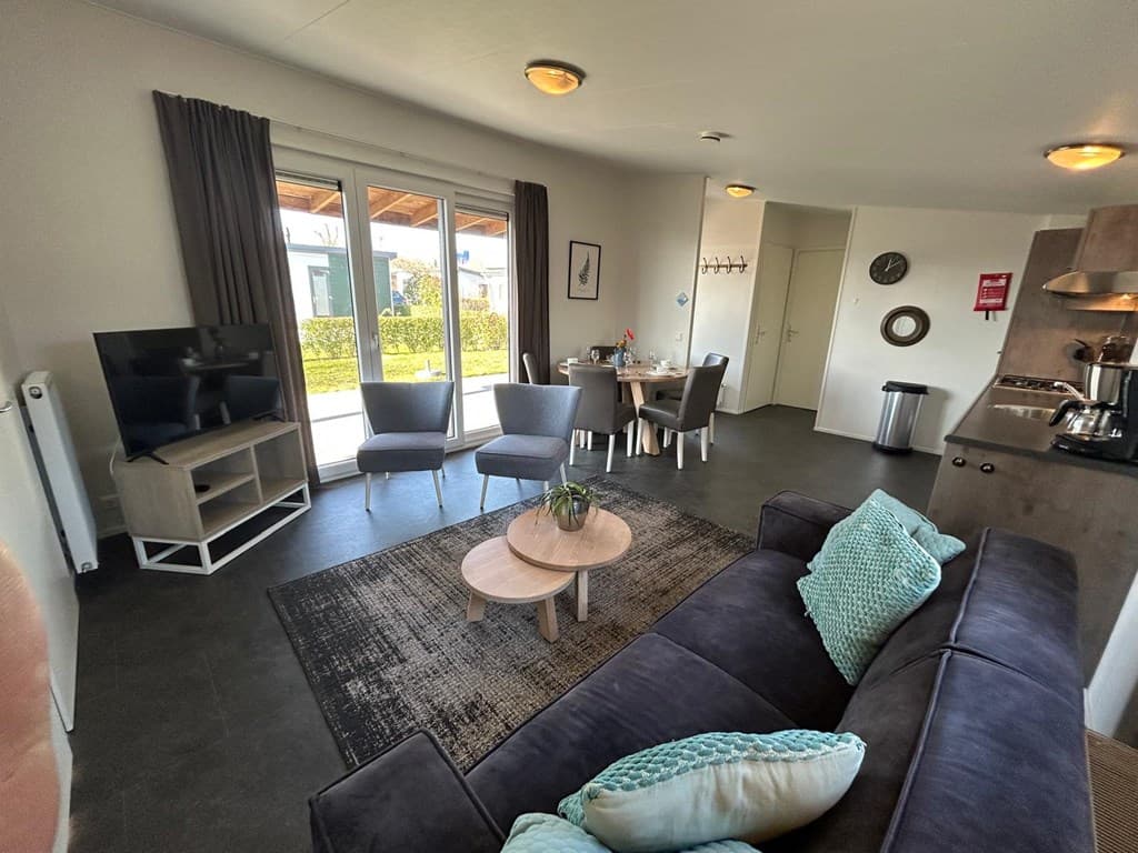 In een woonkamer met comfortabele meubels, een televisie en een eetgedeelte met een tafel en stoelen.