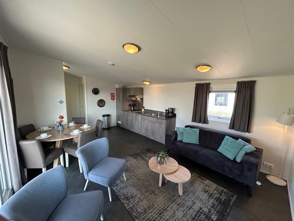 Woonkamer met zithoek, eettafel en open keuken, ingericht in moderne stijl met neutrale kleuren en comfortabele meubels