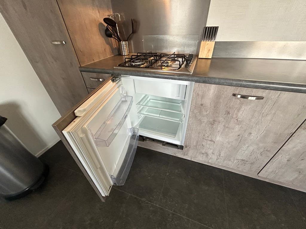 Keuken met een open koelkast, gasfornuis en enkele keukengerei in een moderne uitstraling.