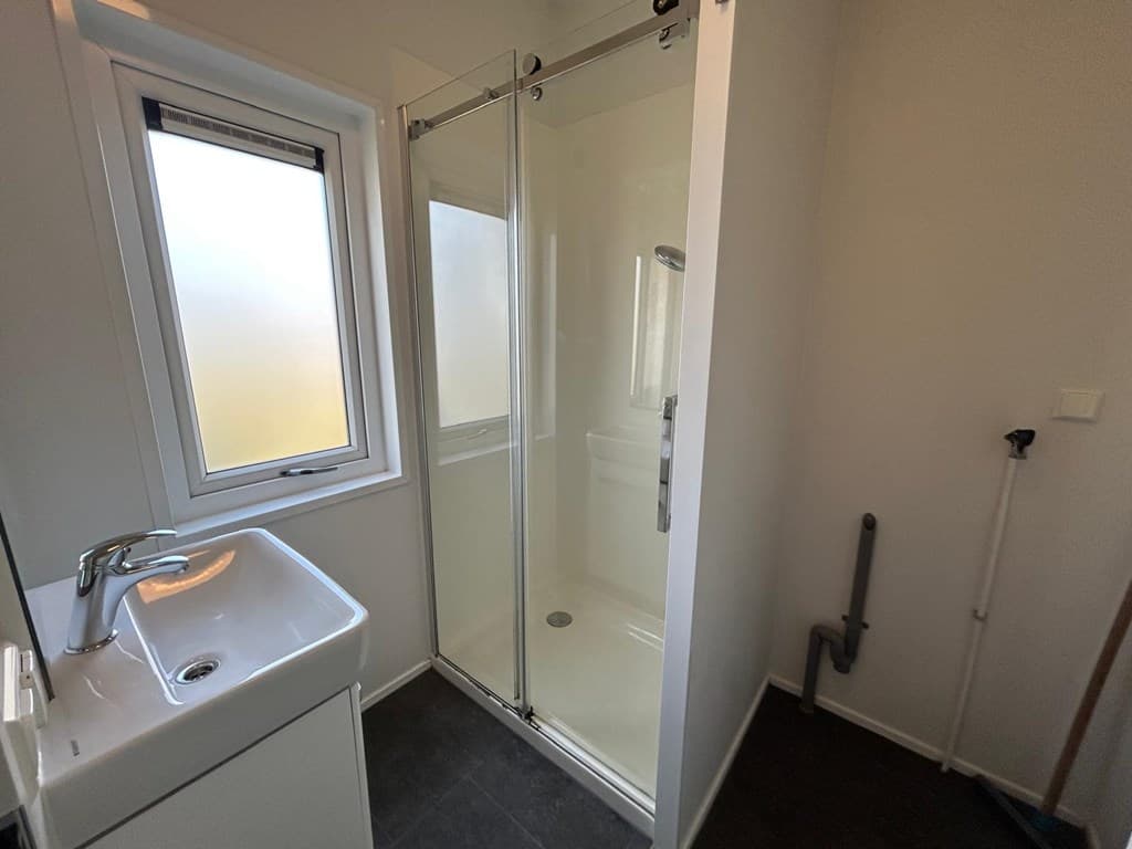 Moderne badkamer met douchecabine, wastafel en raam voor natuurlijke lichtinval