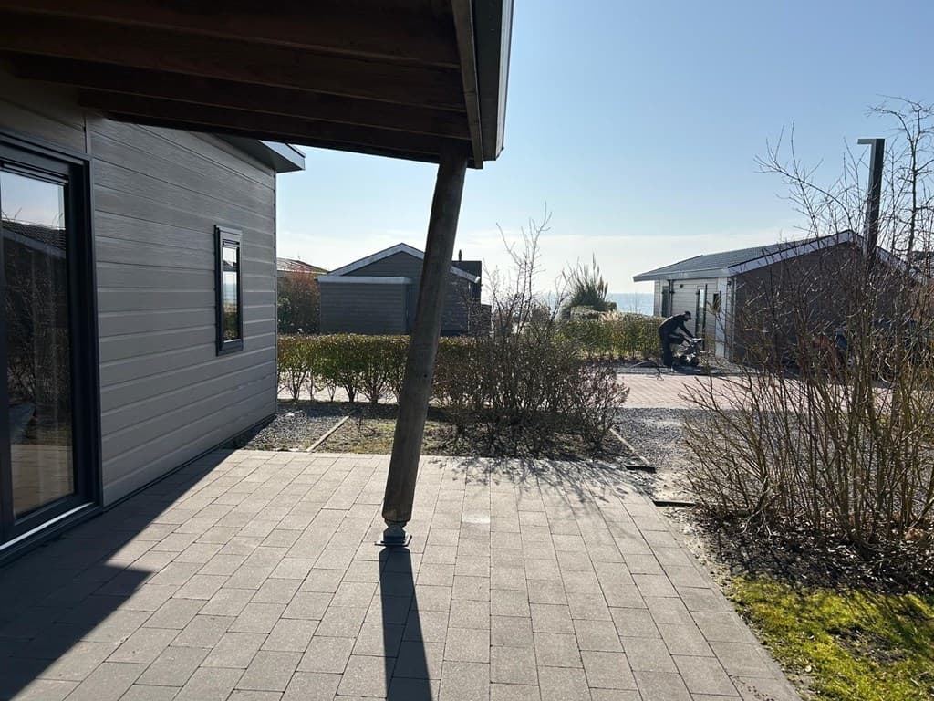 Zicht op een betegeld terras met planten en paden naar andere vakantiehuisjes in EuroParcs Markermeer.