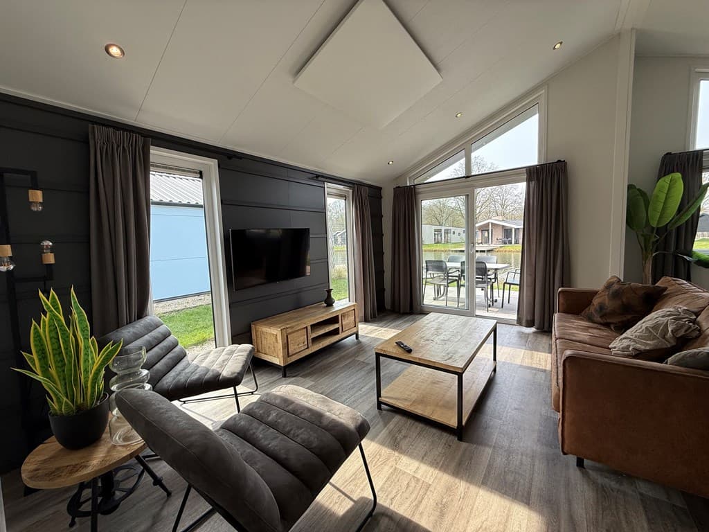 Moderne woonkamer met grote ramen, comfortabele meubels en uitzicht op de tuin bij EuroParcs Kaatsheuvel