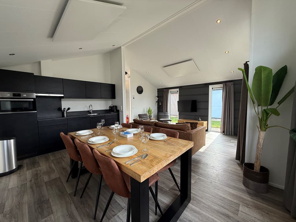 Moderne open keuken met eettafel en zithoek, grote ramen met uitzicht op het buitengebied.