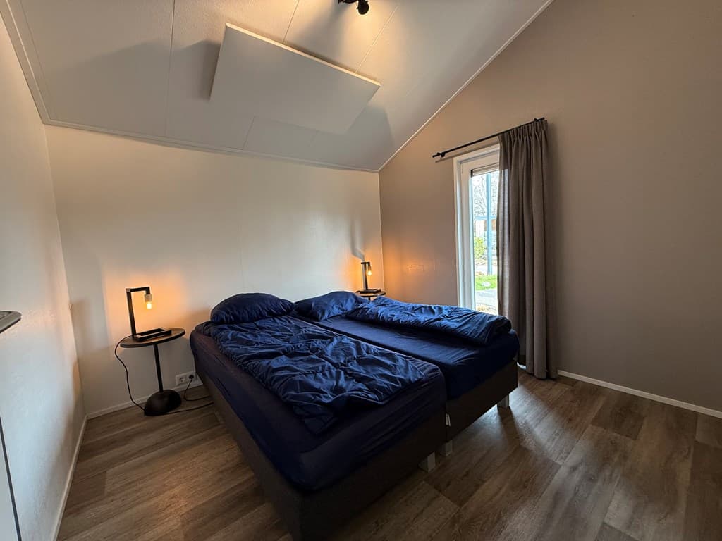 Slaapkamer met twee aparte bedden, een raam met gordijnen en twee lampen op nachtkastjes