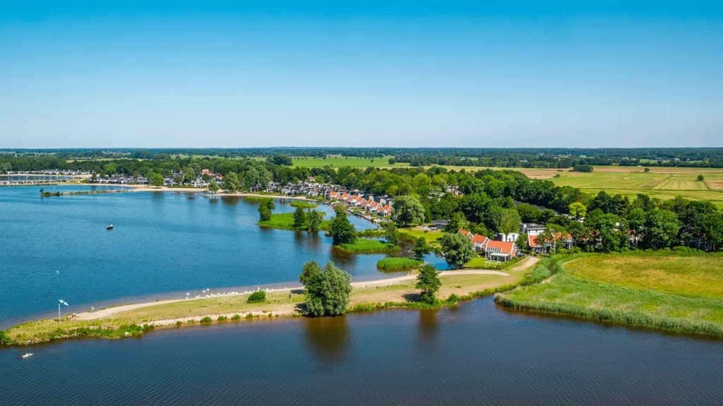 Luchtfoto van EuroParcs Bad Hoophuizen met water en groene omgeving, vakantiehuizen zichtbaar langs de oever.