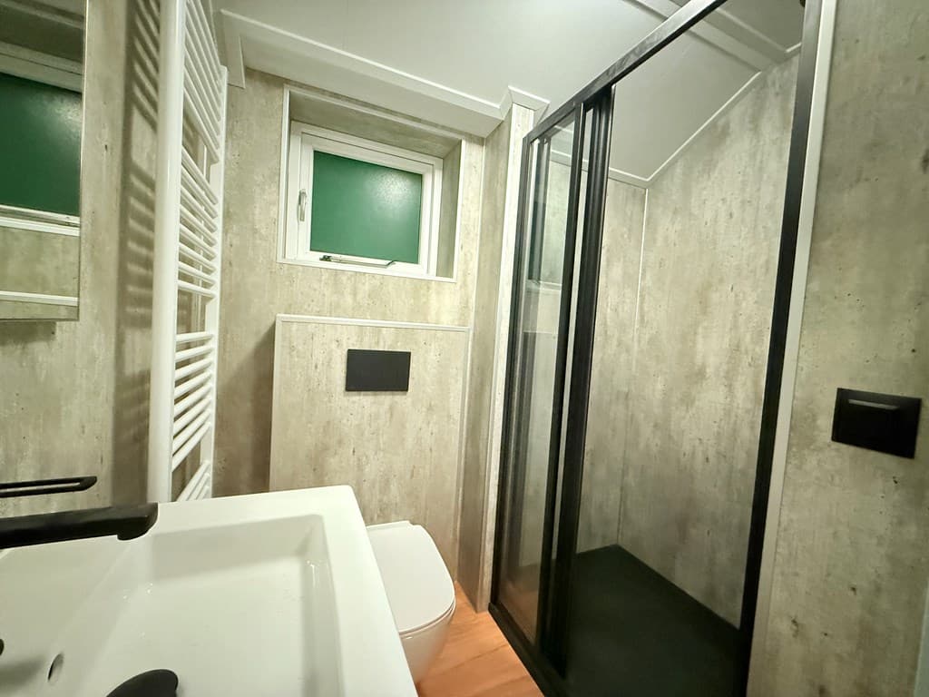 Badkamer met douchecabine, toilet en wastafel, afgewerkt met een moderne, minimalistische stijl.