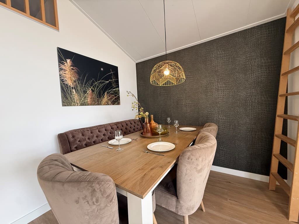 Eethoek met een houten tafel, vier stoelen en een wanddecoratie van gras in een modern interieur.