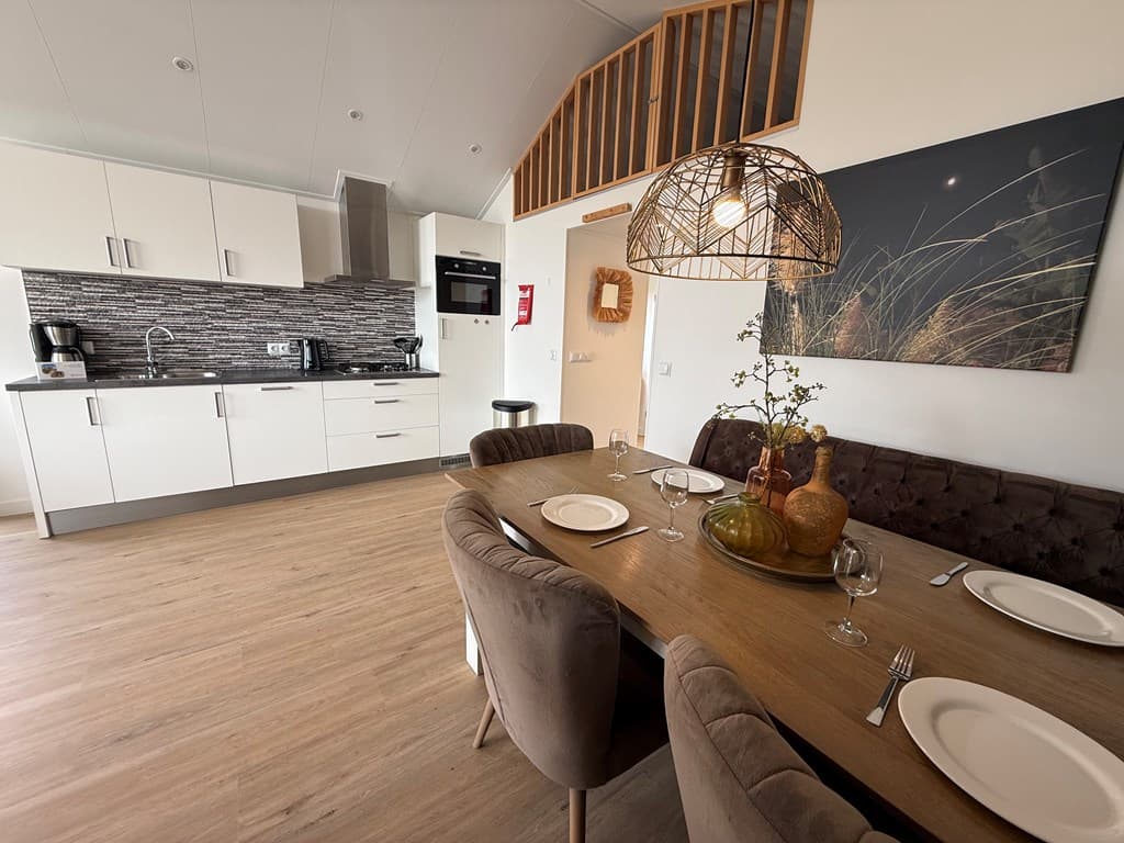 Moderne woning met open keuken, eettafel en zithoek, lichte inrichting en houten vloer.