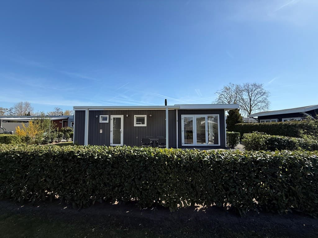 Moderne vakantiewoning met een gevel van hout en een tuinomheining, gelegen in een groene omgeving bij EuroParcs De Biesbosch