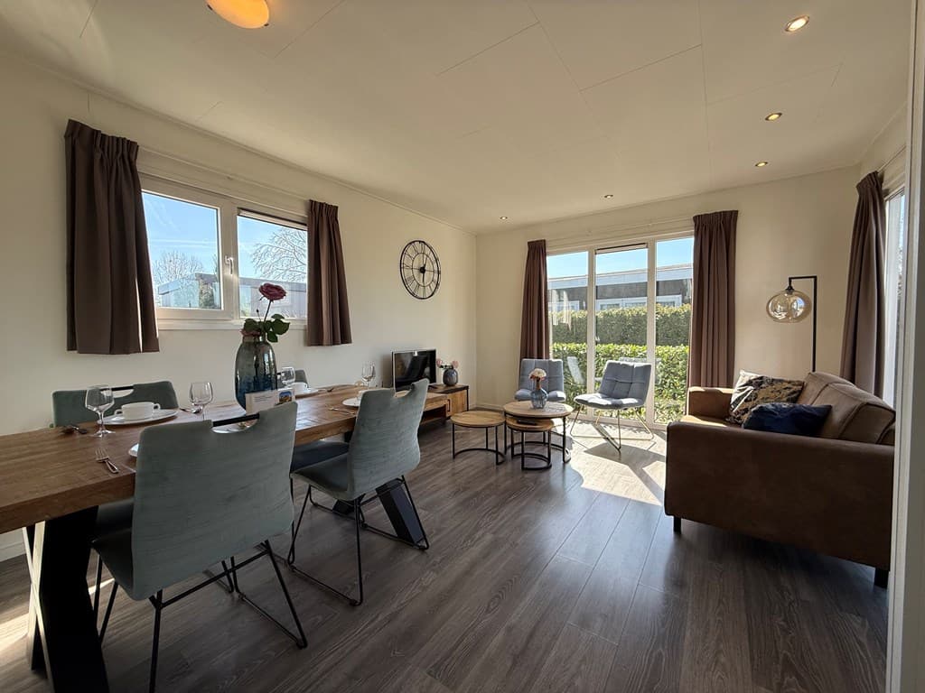 Gezellige woonkamer met eettafel, comfortabele bank en grote ramen voor natuurlijk licht