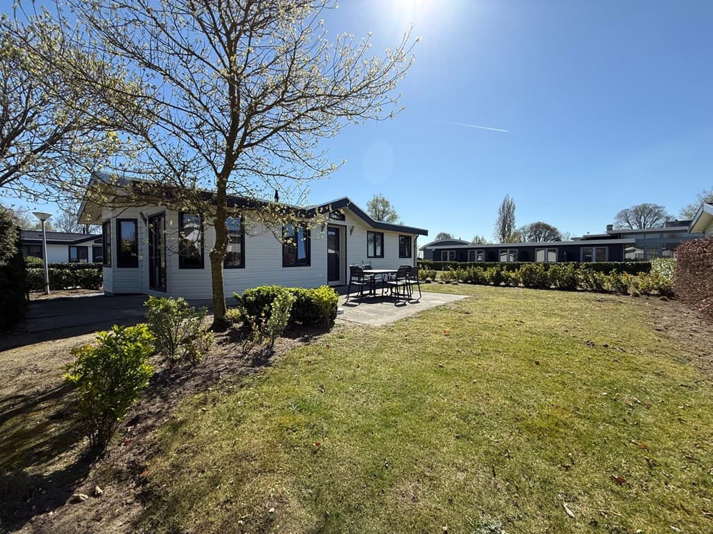 Vakantiewoning met een lichte gevel, terras en tuin in EuroParcs De Biesbosch met groen gras en bomen rondom