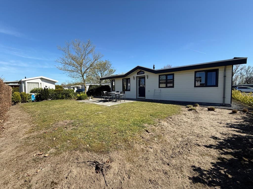 Vakantiewoning met grote tuin en terras, gelegen in EuroParcs De Biesbosch met bomen en andere woningen op de achtergrond