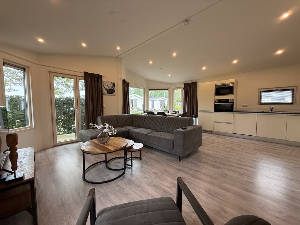 Ruime woonkamer met grote ramen, moderne meubels en open keuken in EuroParcs De Biesbosch, Dordrecht