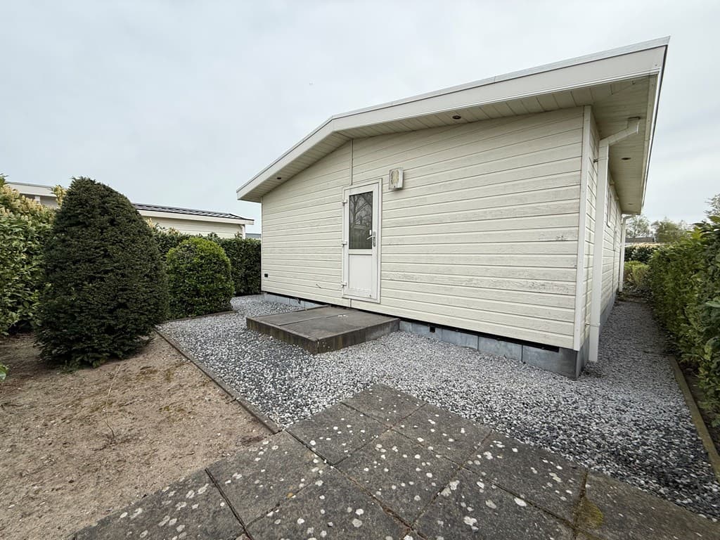 Buitenzicht van een vakantiewoning met een grindpad, gazon en groene heggen in EuroParcs De Biesbosch, Dordrecht