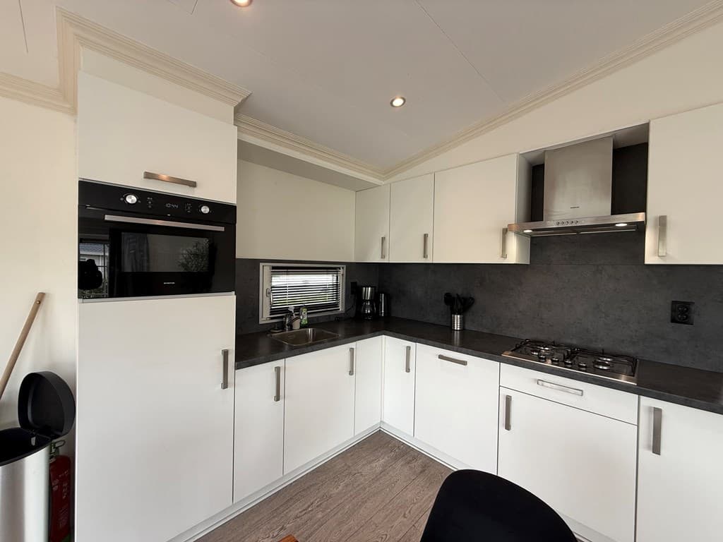 Moderne keukens met witte kasten, gaskookplaat en oven in EuroParcs De Biesbosch, Dordrecht.