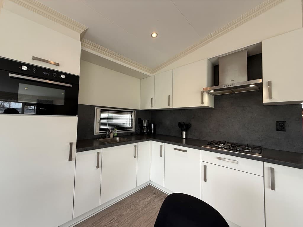 Moderne keuken met witte kasten, donkere werkbladen en inbouwapparatuur in EuroParcs De Biesbosch.