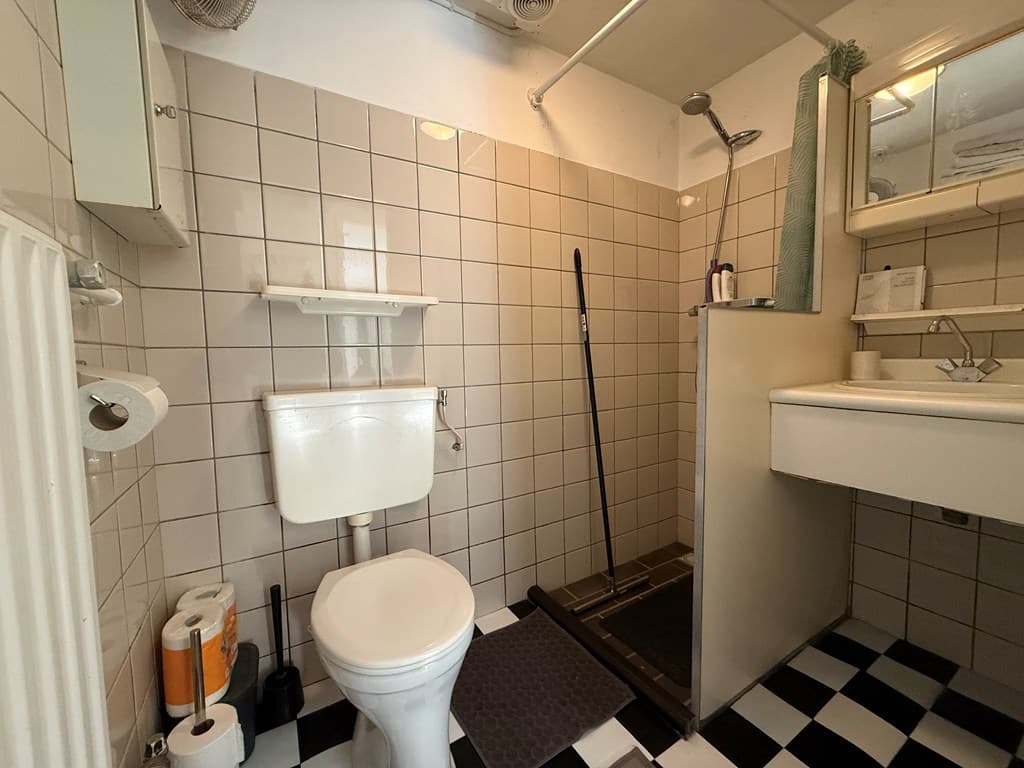 Badkamer met douche, toilet, wastafel en betegelde wanden in zwart-wit motief