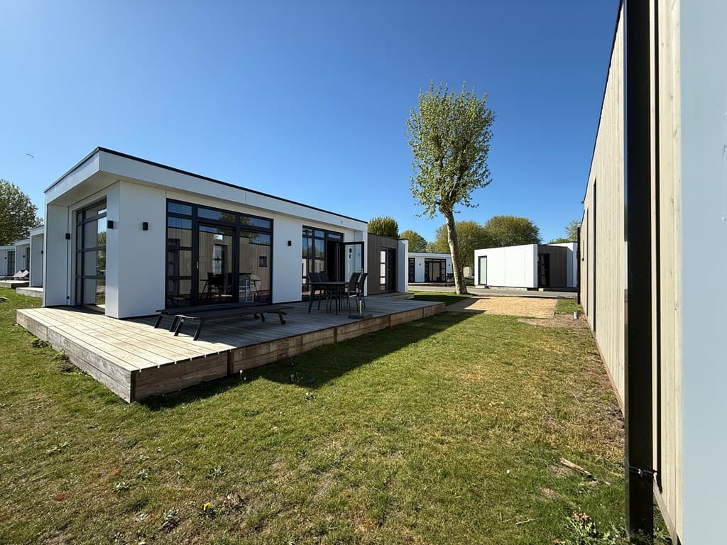 Twee moderne vakantiewoningen met houten terrassen en groen grasveld op MarinaPark Bad Nederrijn.