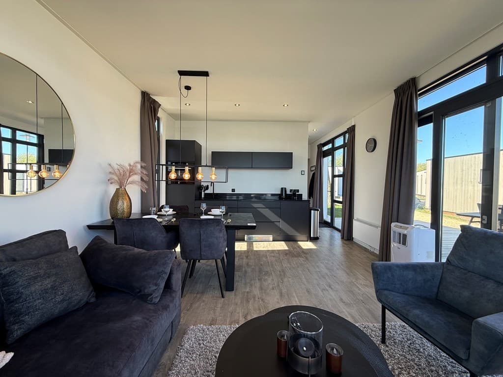 Moderne woonkamer met open keuken, grote ramen, eetruimte en sfeervolle verlichting in MarinaPark Bad Nederrijn.