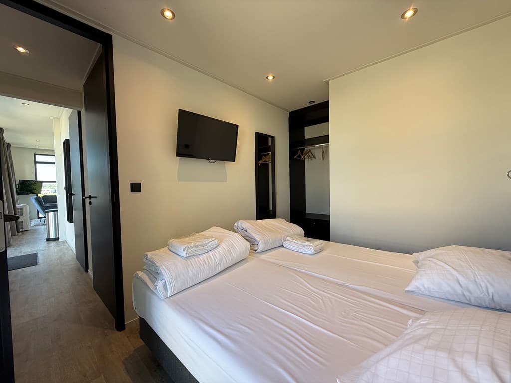 Slaapkamer met twee eenpersoonsbedden, televisie aan de muur en kledingkast in MarinaPark Bad Nederrijn.