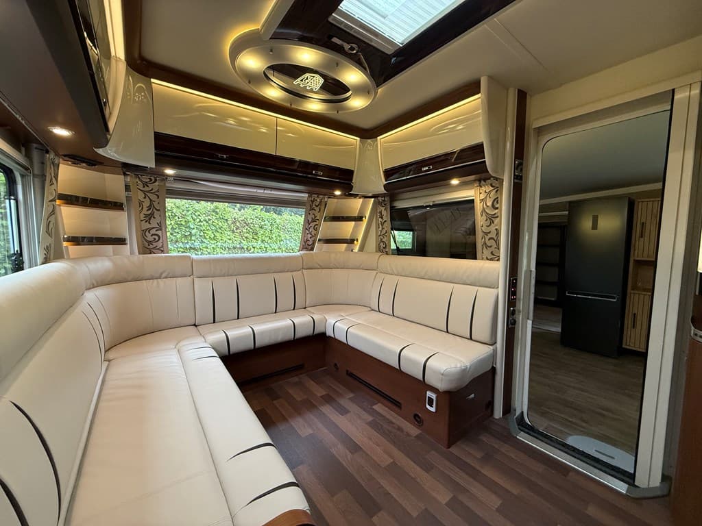 Loungebank met witte bekleding en houten accentuering in een sfeervolle ruimte met grote ramen en moderne verlichting