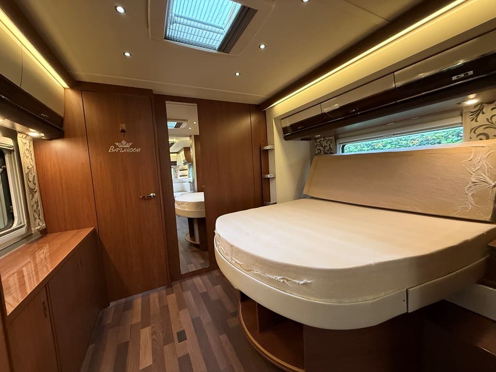 Slaapkamer met een tweepersoonsbed, opbergkasten en verlichting, in een houten interieur met moderne afwerking