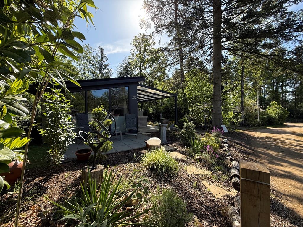 Moderne vakantiewoning met terras, omringd door bomen en groen, gelegen op het Veluwepark de Bosgraaf.