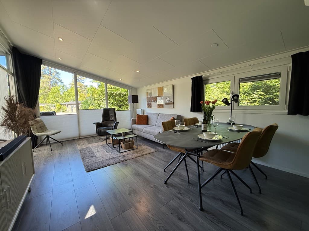Licht en modern interieur met een zithoek, eettafel en grote ramen voor veel natuurlijk licht.