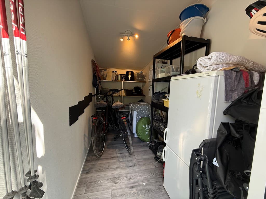 In de opslagruimte staan fietsen, kasten met opbergruimte en verschillende accessoires zichtbaar.