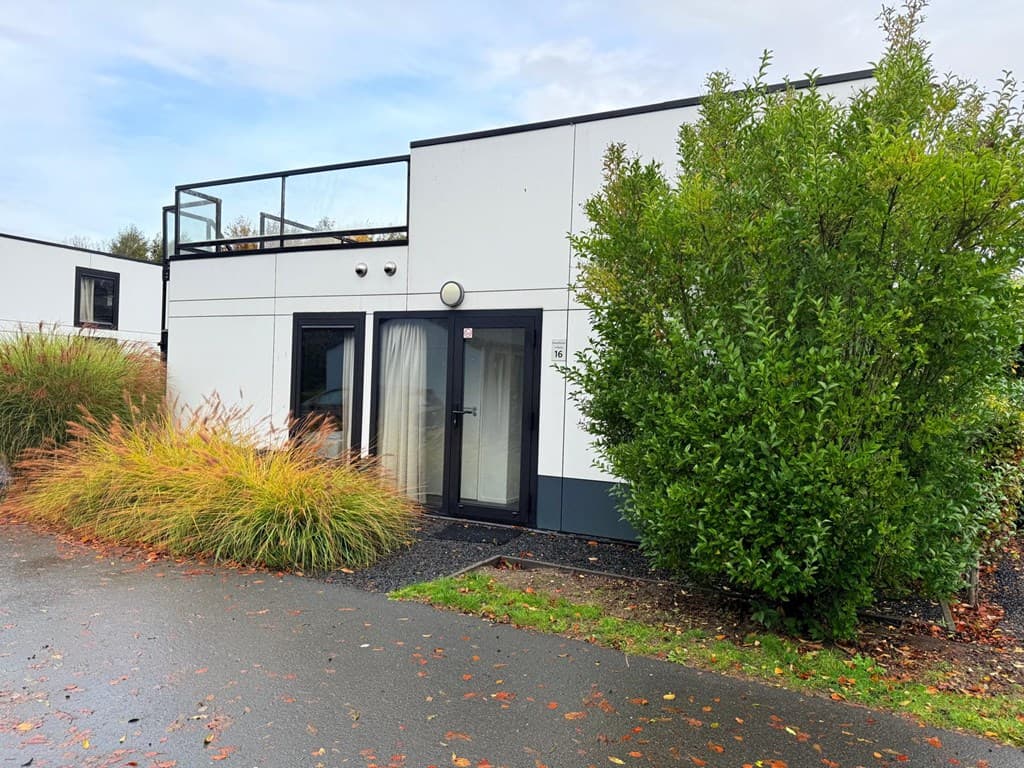 Moderne vakantiewoning met een groene struik en een omheinde voorzijde, gelegen bij EuroParcs Bad Hoophuizen.