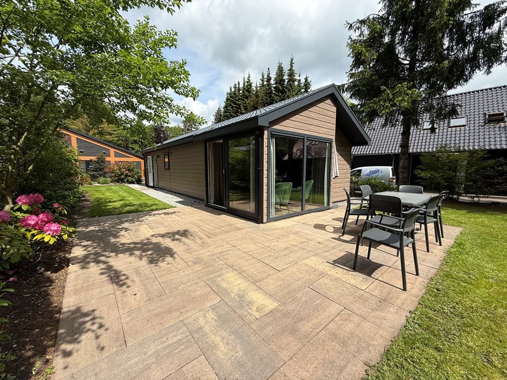 Moderne vakantiewoning met terras en tuin, omgeven door bomen en groene planten op EuroParcs Resort De Utrechtse Heuvelrug.