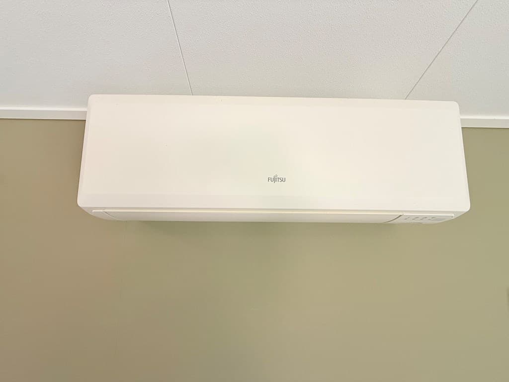 Wandairconditioner gemonteerd aan de muur in een kamer met een beige kleur.