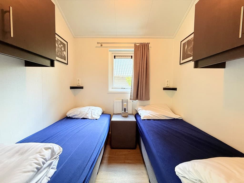 Slaapkamer met twee eenpersoonsbedden, gelaagd linoleum, wandplanken en een raam met uitzicht naar buiten