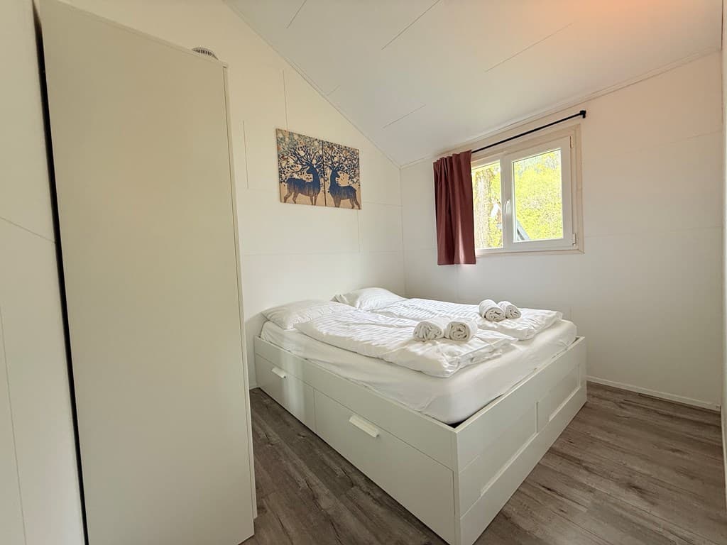 Slaapkamer met twee bedden, kledingkast, raam met uitzicht en kunstwerk aan de muur