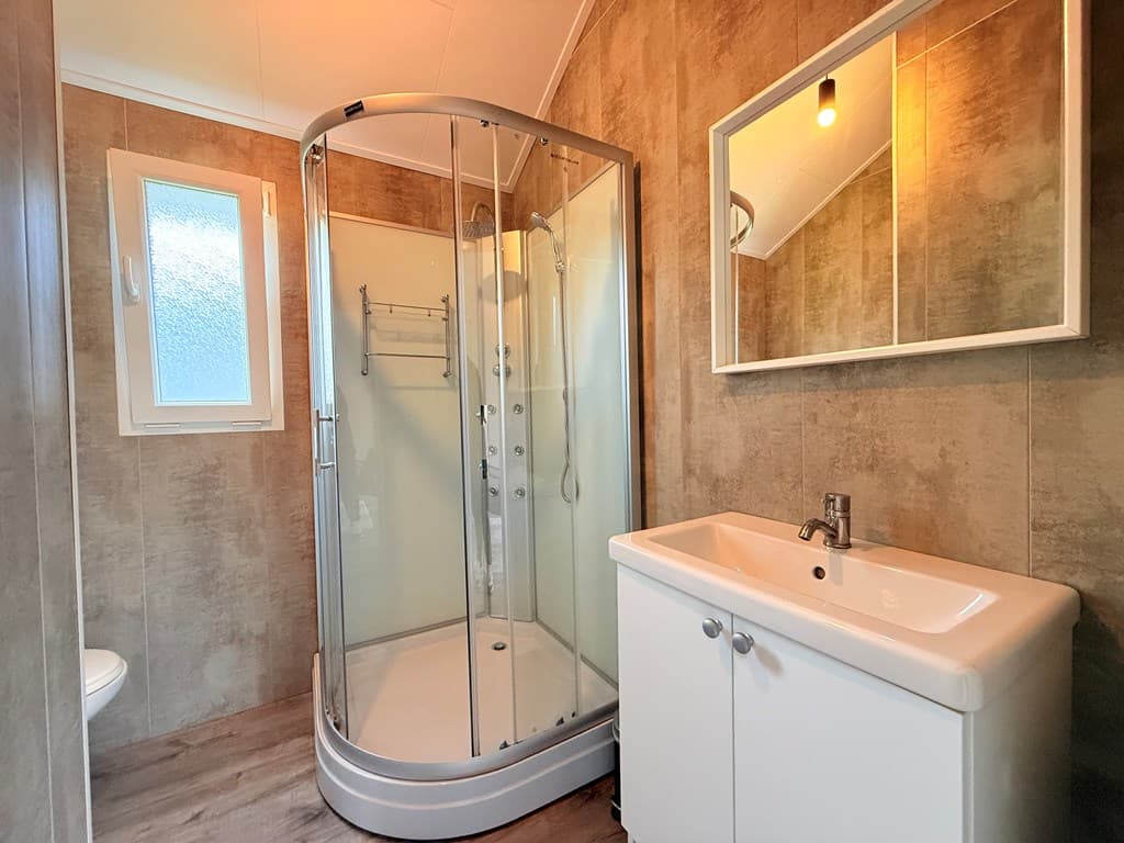 Moderne badkamer met douchecabine, wastafel en spiegel, verlichting en raam voor natuurlijk licht
