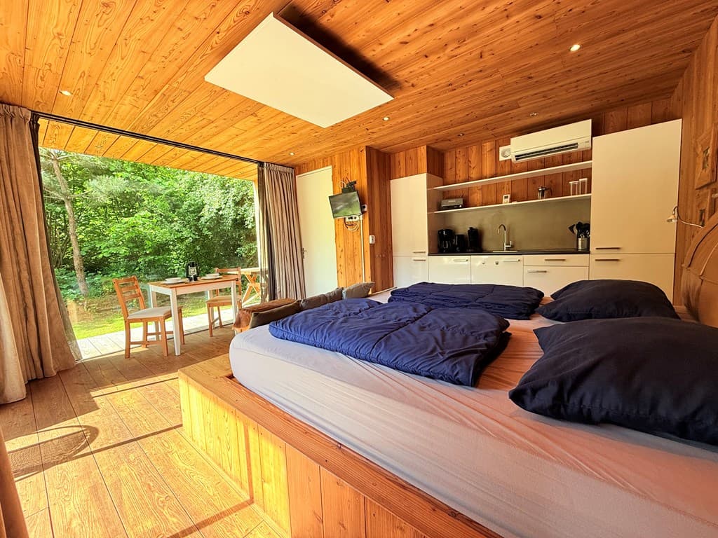 Sfeervolle vakantiewoning met een houten interieur, een tweepersoonsbed en uitzicht op een buitenruimte met een tafel en stoe