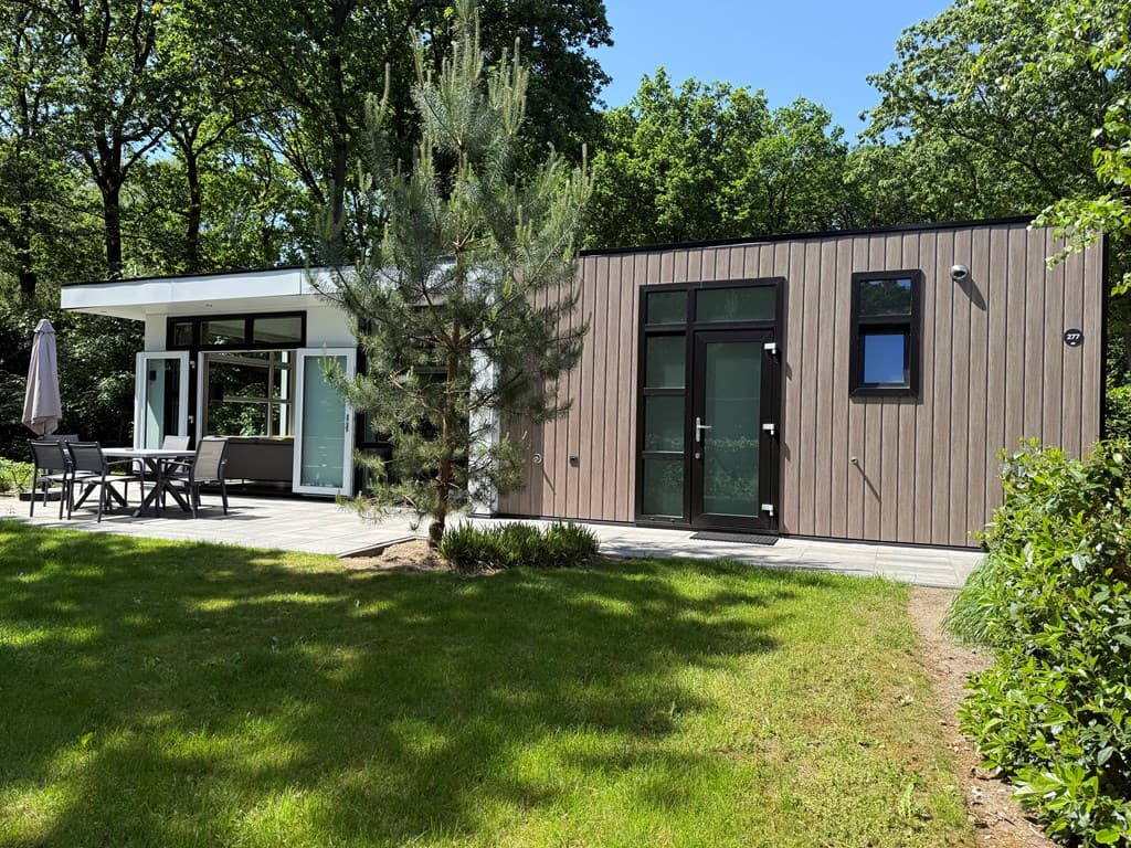 Moderne vakantiewoning met houten gevel, terras en uitzicht op groene bomen en verhoogd grasveld.