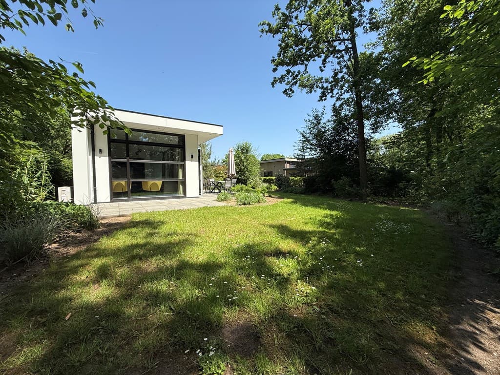 Moderne vakantiewoning omringd door groen, met een ruime tuin en zonovergoten terras.