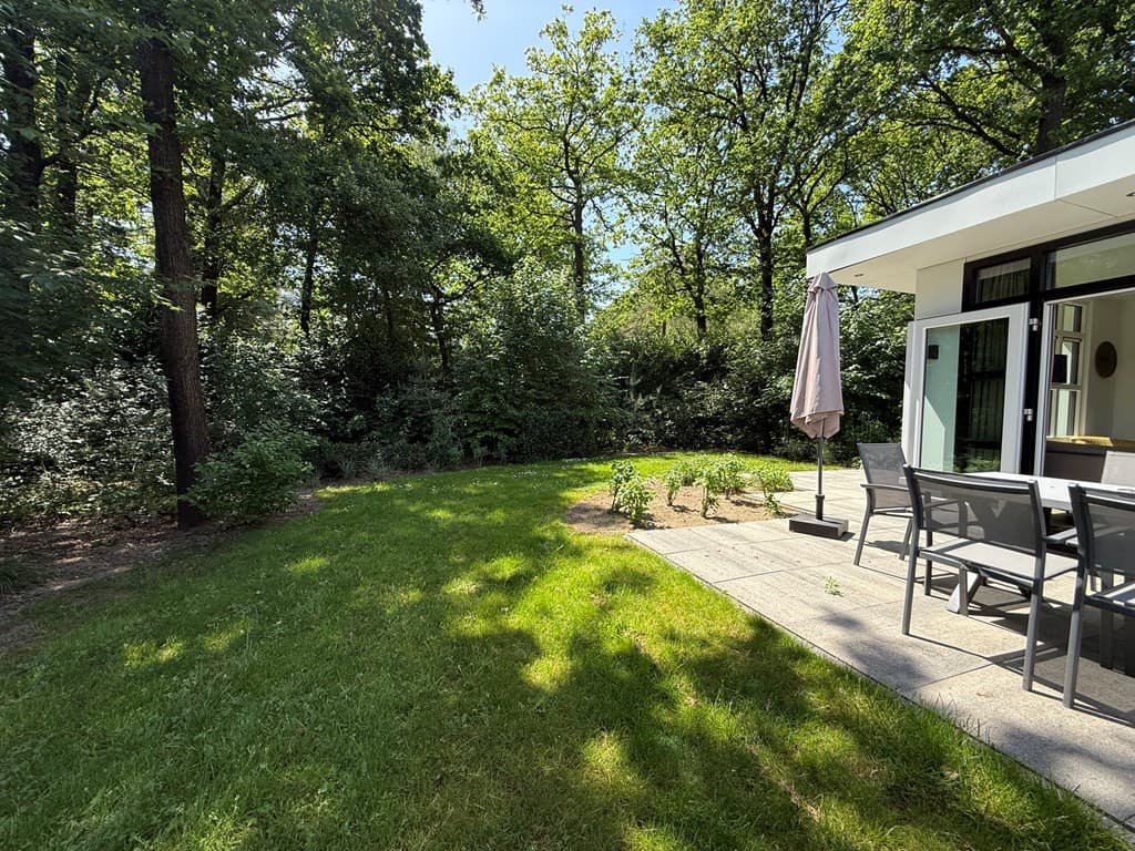 Terras met tuinmeubels en parasol, omgeven door groen en bomen in een rustige omgeving
