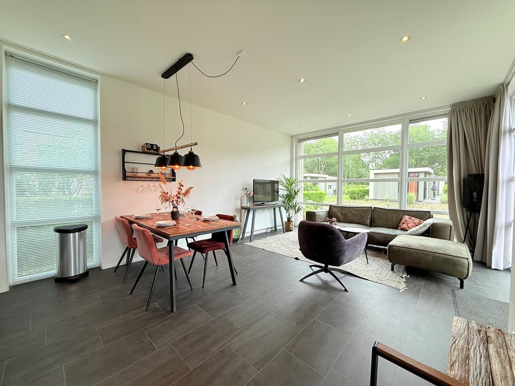 Moderne woonkamer met eettafel, comfortabele bank en grote ramen voor natuurlijk licht
