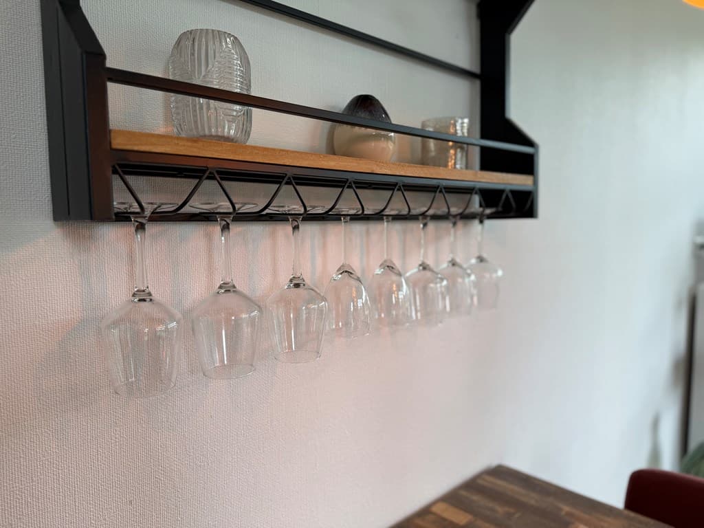 Glazen hangen op een houten rek aan de muur, met een aantal decoratieve items ernaast.