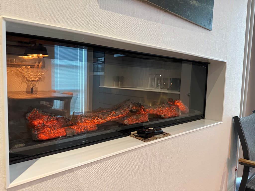 Ingebouwde sfeerhaard met gloeiende houtstammen in een nis aan de muur.