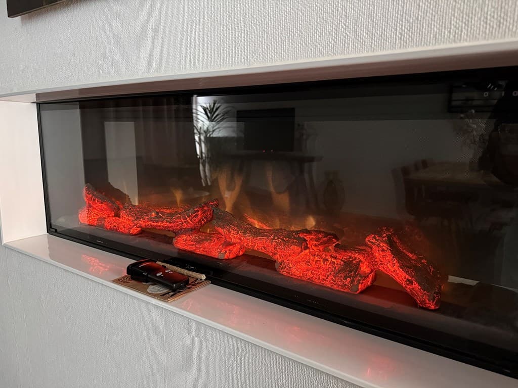 Ingebouwde elektrische haard met vlammen en houtlook in een moderne woonkamer.