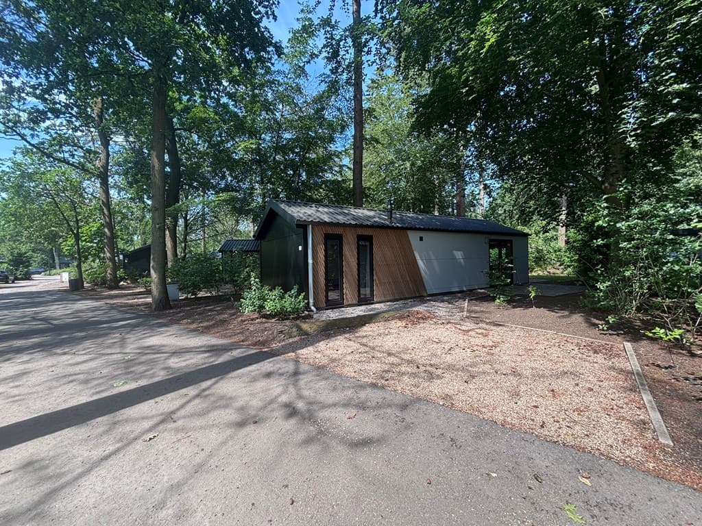Vakantiewoning in EuroParcs Resort De Utrechtse Heuvelrug, omgeven door bomen met een grindpad en verharde toegang.