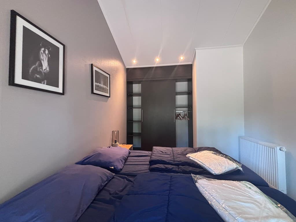 Slaapkamer met twee eenpersoonsbedden, kast met louverdeuren en wanddecoratie van foto's.