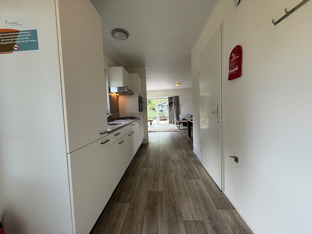 Ingang van de vakantiewoning met een lange gang en een keuken aan de rechterzijde, uitzicht op de woonkamer aan het einde.