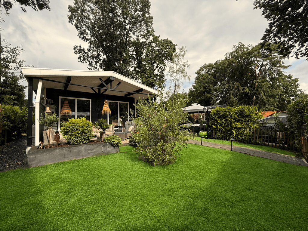 Recreatiewoning met een ruime groene tuin, terras met overkapping en omliggend hekwerk op Camping De Konijnenberg.