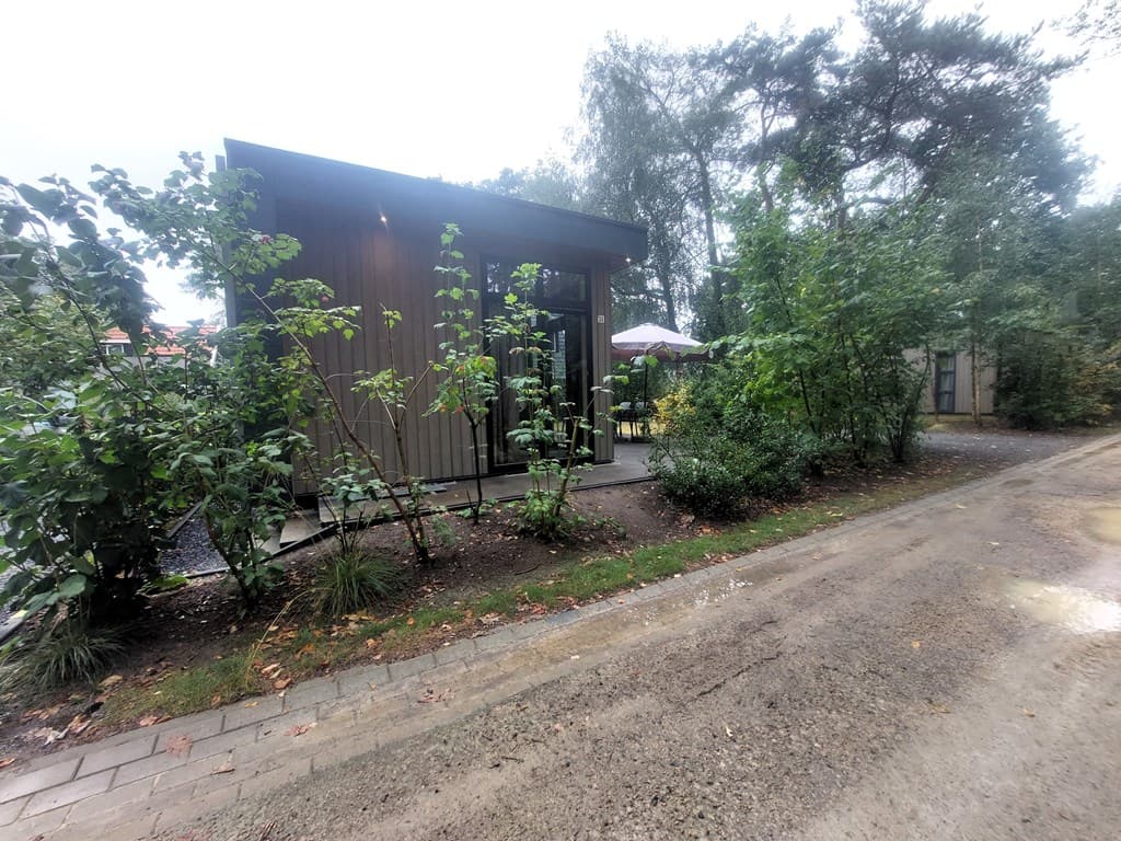 Recreatiewoning met houten gevel, omgeven door groen en naast een grintpad in EuroParcs De Zanding