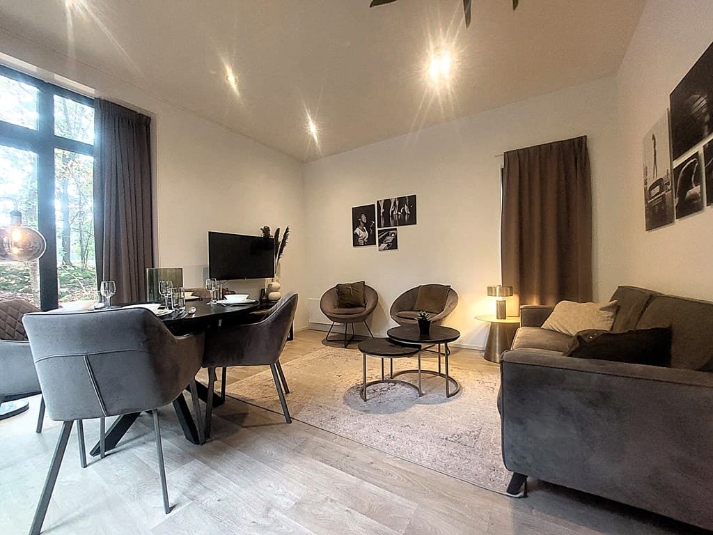 Moderne woonkamer met een zithoek, eettafel en grote ramen met uitzicht op de natuur